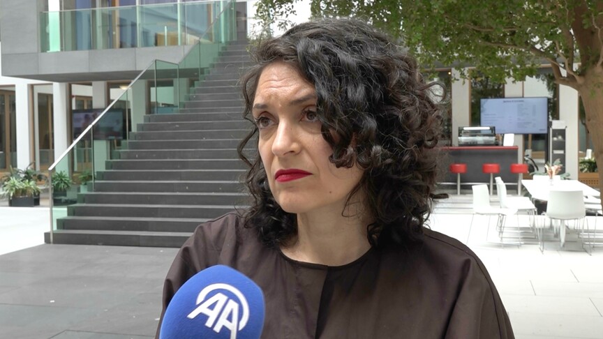 Almanya bayrağı önünde duran bir grup insan.