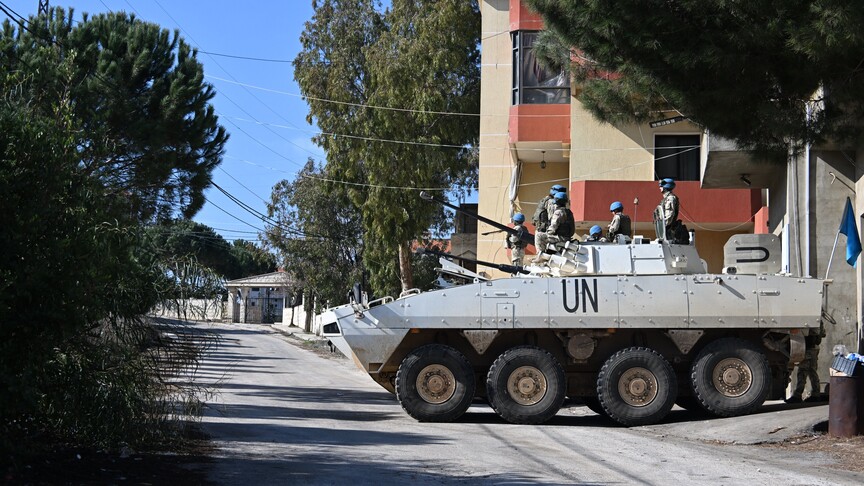 Birleşmiş Milletler bayrağı önünde duran BM Barış Gücü askerleri.