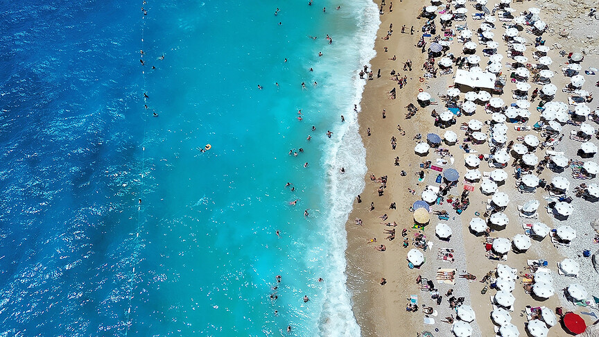 Antalya'da plajda güneşlenen turistler ve turkuaz renkli deniz.