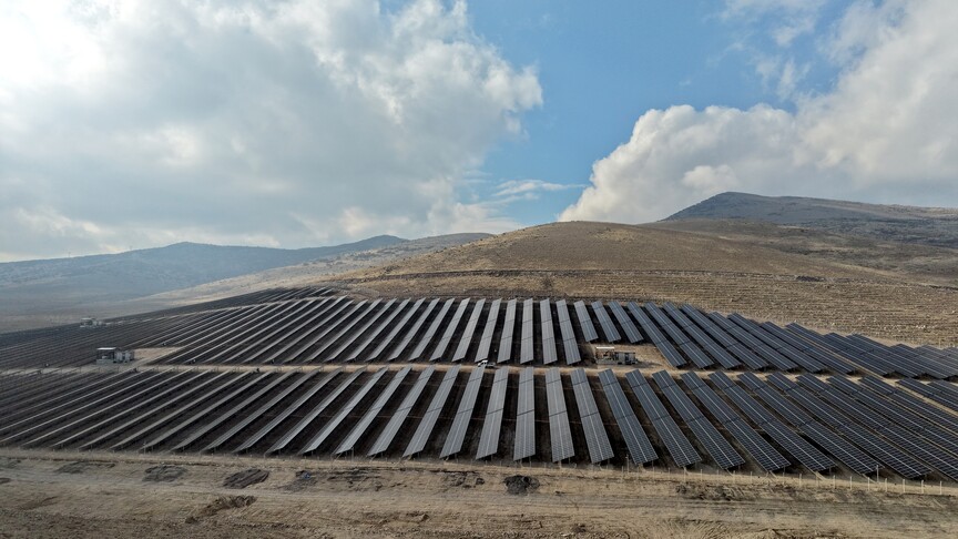 Güneş panelleriyle dolu bir enerji santralinin havadan görünümü.