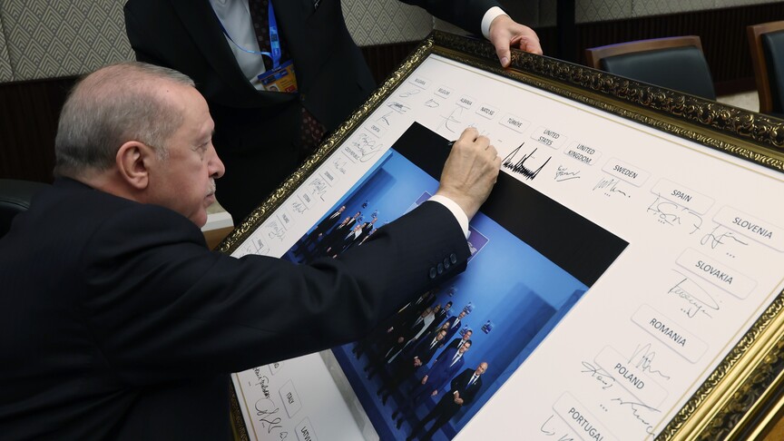 Cumhurbaşkanı Recep Tayyip Erdoğan, NATO Zirvesi'nde çekilen aile fotoğrafını imzalıyor.